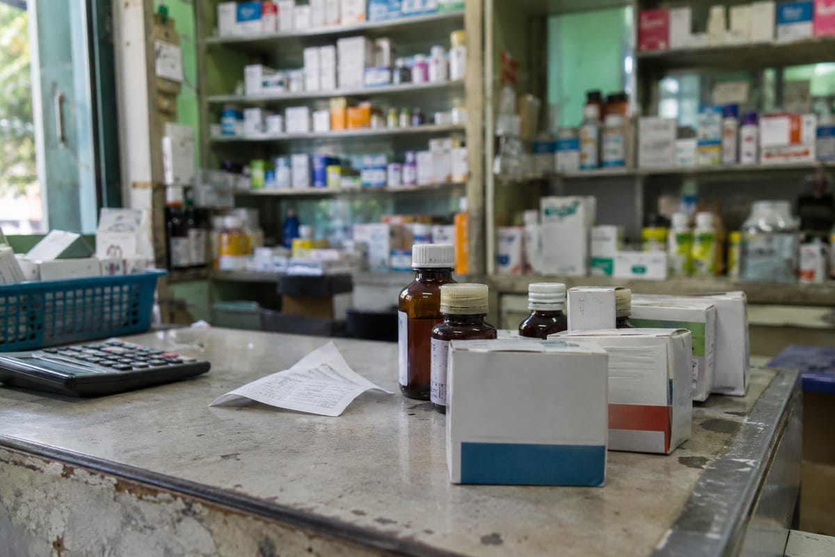 Representational AI illustration of unbranded medicine boxes and bottles on a pharmacy counter.
