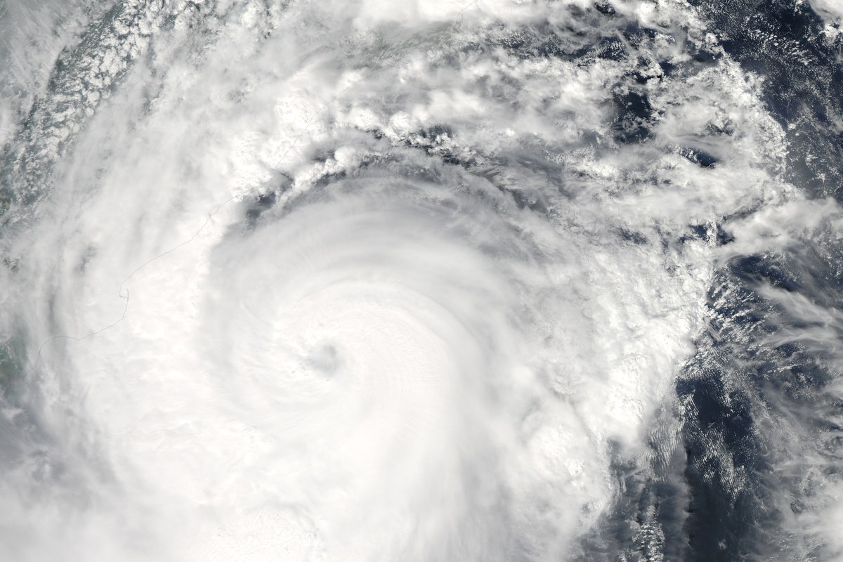 Satellite view of a large cyclone with a tight spiral of white cloud bands over dark blue sea.