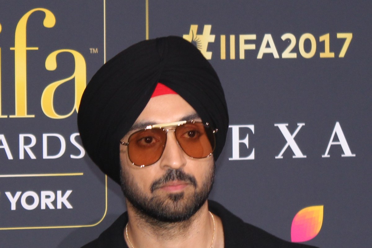 Diljit Dosanjh in a black turban, tinted aviator sunglasses and a black jacket in front of an IIFA 2017 backdrop.