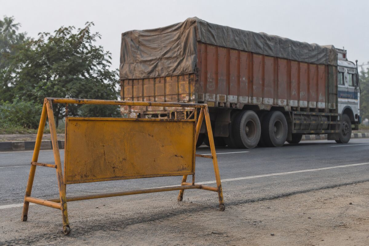 AI-generated representational image of a metal roadside barricade with a stationary goods truck in the background