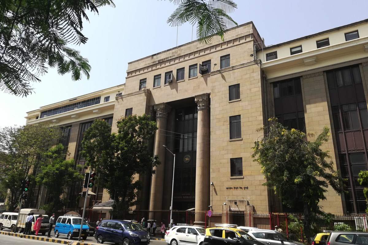 A sandstone Reserve Bank of India office building in Mumbai with cars parked along the street in front.