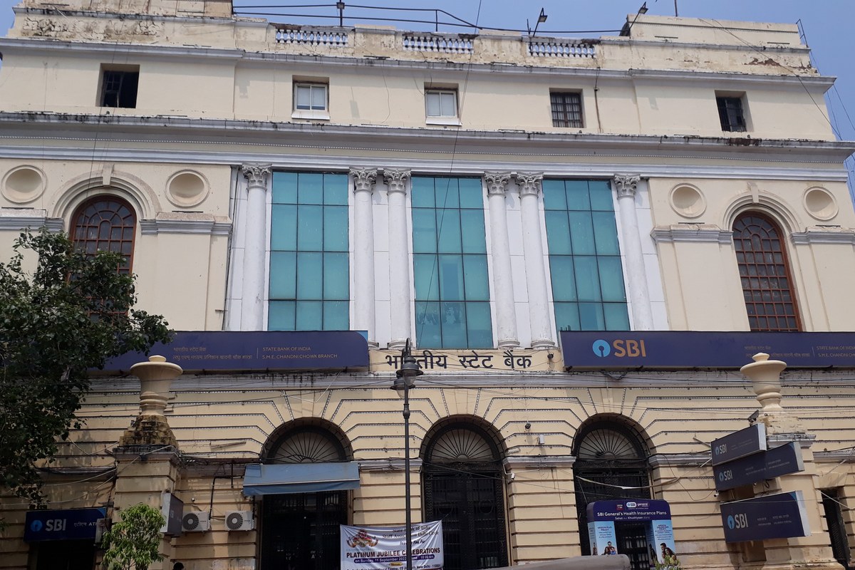 The cream-coloured colonial-era facade of the State Bank of India’s Chandni Chowk branch in Old Delhi, with blue SBI signboards in English and Hindi.