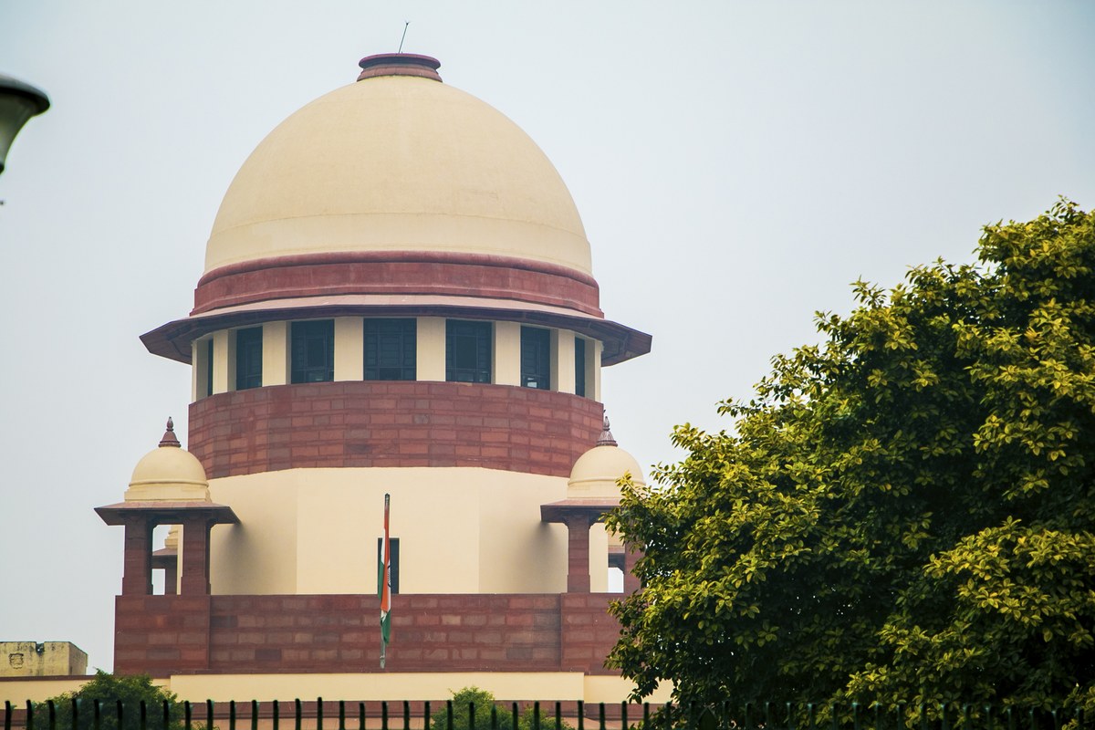 The domed central wing of the Supreme Court of India in New Delhi, with trees in the foreground.